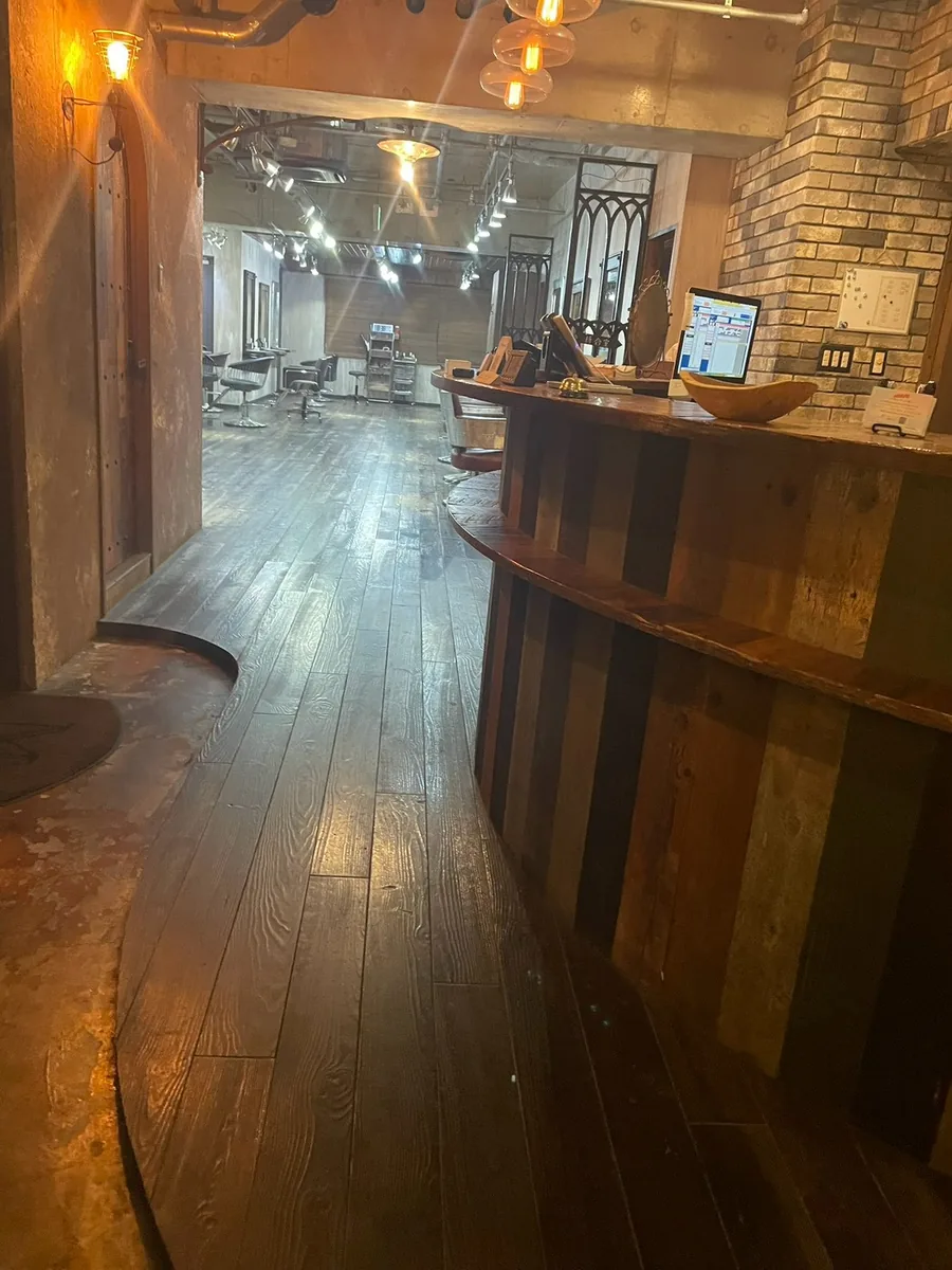 入口から見た店内。木目の床と古材を組み合わせた円形カウンター、奥にセット面が並ぶ