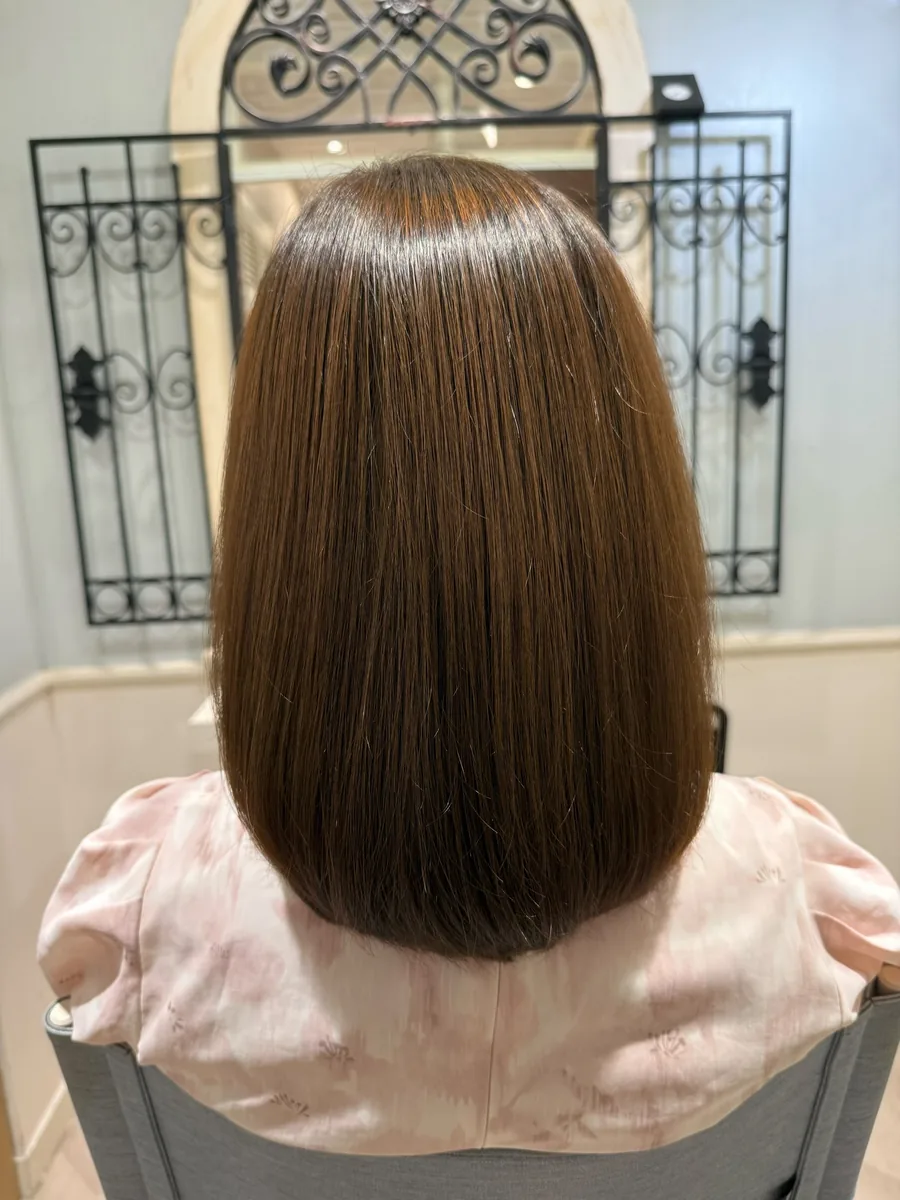 アフター。うねりが収まり、毛先まで面のそろった艶のあるミディアムヘア。
